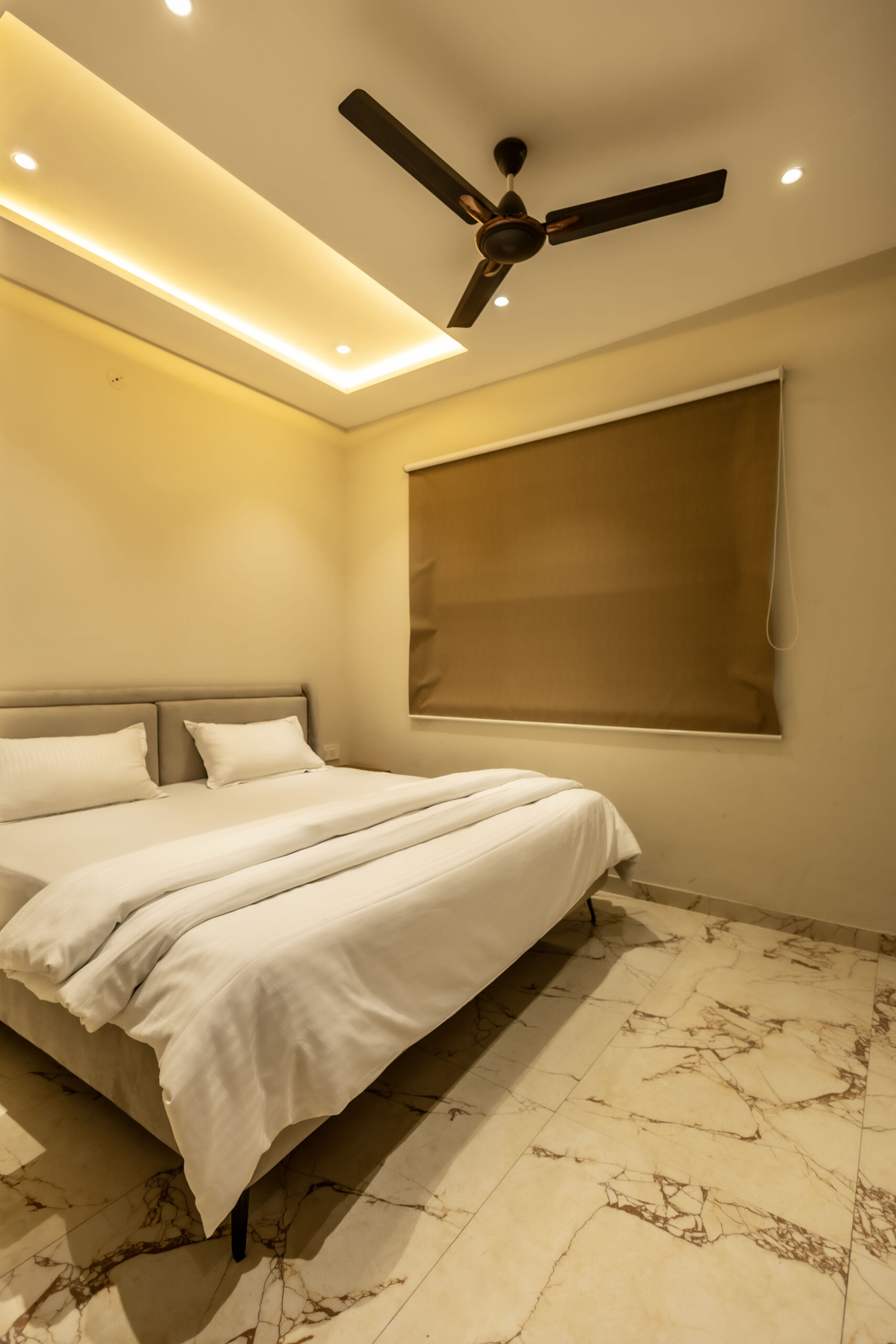 A stylish bedroom showcasing a ceiling fan and a bed, designed for serviced apartments in Indore